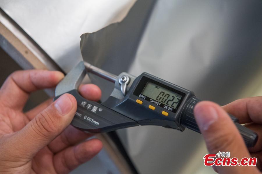 A worker shows stainless steel 0.02 millimeters thick at a company in Taiyuan City, the capital of North China’s Shanxi Province, Aug. 8, 2018. The company started mass production of the advanced 0.02-millimeter-thick, 600-millimeter-wide stainless steel, which is said to have wide applications in a range of fields, including aerospace, automotive, electronics and computers. Sources said due to difficult production techniques, China used to import the product from Japan and Germany. (Photo: China News Service/Wei Liang)