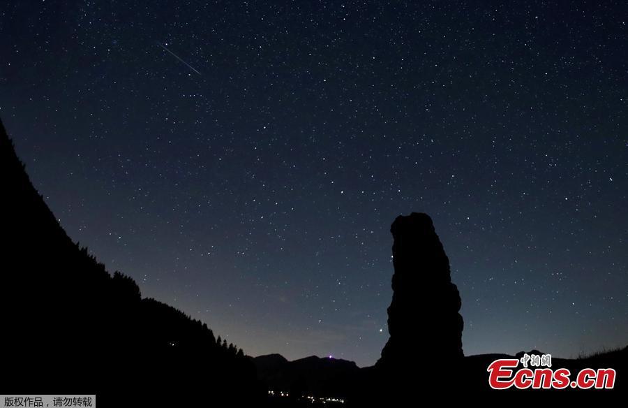 A meteor streaks past stars in the night sky next to the Cornieule of Tomeley standing stone during the annual Perseid meteor shower in La Forclaz, Switzerland August 11, 2018. (Photo/Agencies)
