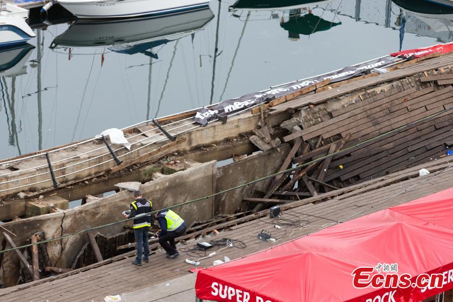 Two police investigators inspect the seafront platform in Vigo on August 13, 2018 after a section of a wooden promenade suddenly collapsed with people watching a rap artist just before midnight on Sunday. More than 300 people were injured, including nine seriously, the regional government of Galicia said in a statement. (Photo/Agencies)