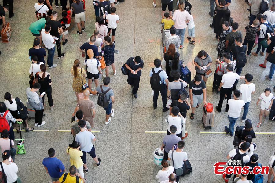 Passengers wait to change or refund tickets at a railway station in Shanghai, Aug. 13, 2018, after several trains were canceled due to Typhoon Yagi. Emergency rescuers are bracing for this year\'s 14th typhoon in the metropolis. (Photo: China News Service/Yin Liqin)