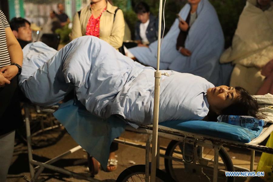 An injured person is transferred to safety area in Tonghai County, southwest China\'s Yunnan Province, Aug. 13, 2018. Eighteen people were injured after a magnitude-5 earthquake jolted Yunnan Province Monday morning, local authorities have said. The quake affected more than 48,000 residents in the counties of Tonghai and Huaning and the district of Jiangchuan, all administered by the city of Yuxi, damaging over 6,000 homes, according to a statement from the provincial civil affairs department. (Xinhua/Wang Anhaowei)