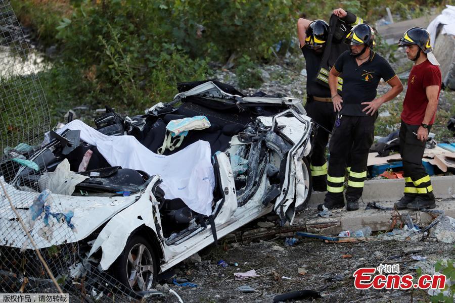 Firefighters stand next to a crushed car at the collapsed Morandi Bridge site in the port city of Genoa, Italy August 14, 2018. The bridge connects the highway A10 to the western part of the city, near a populous neighborhood called Sampierdarena. At least 26 people were killed in the accident. (Photo/Agencies)
