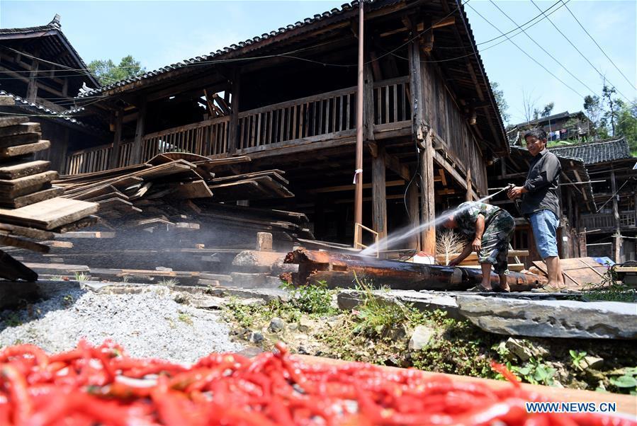 Villagers clean wood at an old wooden house in reform in Zaidang, Qiandongnan of southwest China\'s Guizhou Province, Aug. 14, 2018. Zaidang, a village of Dong ethnic group, has encouraged its villagers to make use of idle resources to upgrade local infrastructure, in an aim to develop tourism industry and shake off poverty. (Xinhua/Wang Bingzhen)