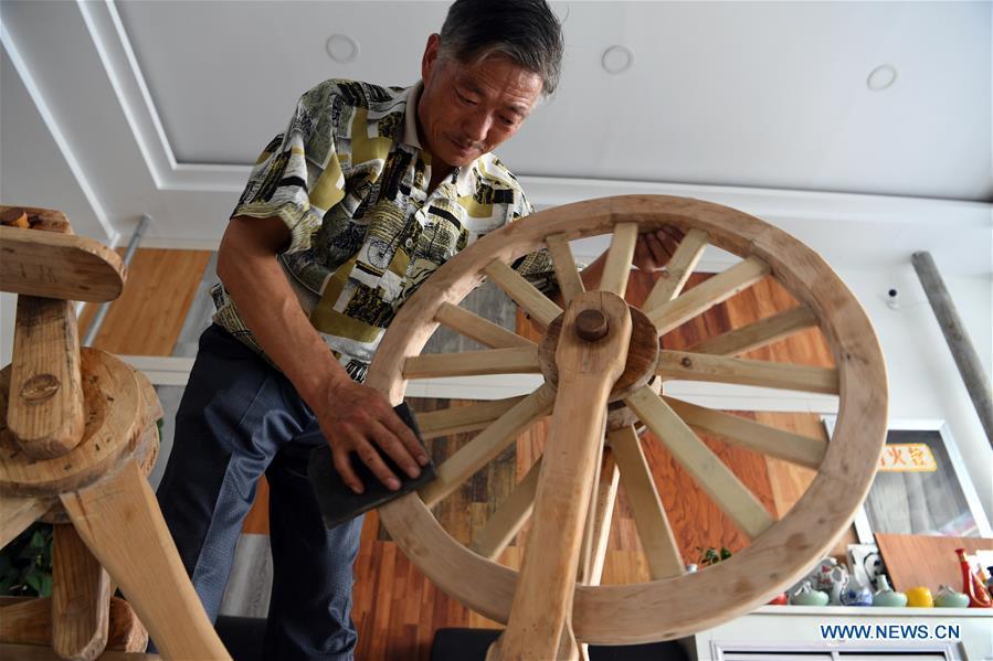 He Yong polishes the wheel of a wooden bicycle in Liuhu Township of Pingliang City, northwest China\'s Gansu Province, Aug. 14, 2018. The 55-year-old farmer He Yong successfully made a 1.8-meter-long and 0.98-meter-high wooden bicycle in 2017. The bike was made purely of wood, including walnut and elm. (Xinhua/Fan Peishen)