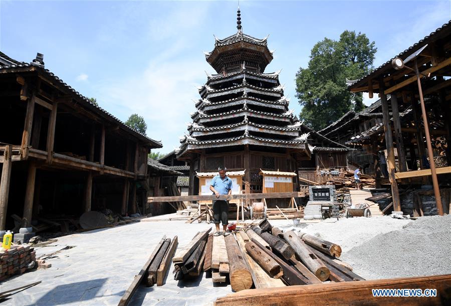 A villager carries wood at an old wooden house in reform in Zaidang, Qiandongnan of southwest China\'s Guizhou Province, Aug. 14, 2018. Zaidang, a village of Dong ethnic group, has encouraged its villagers to make use of idle resources to upgrade local infrastructure, in an aim to develop tourism industry and shake off poverty. (Xinhua/Wang Bingzhen)