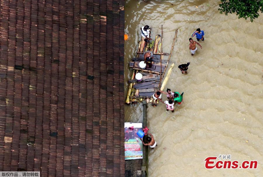 People wait for aid next to makeshift raft at a flooded area in the southern state of Kerala, India, August 19, 2018. Incessant downpours since Aug. 8 have caused the worst floods in a century in the southwestern state, and close to 200 people have perished in the rising waters and landslides. (Photo/Agencies)
