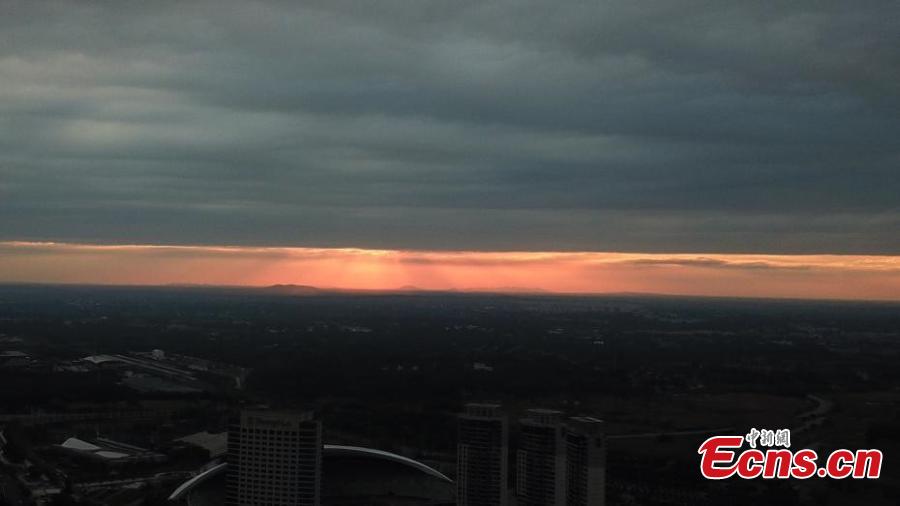 Dark clouds create a distinct line in the sky as the sun sets over Yangzhou City, Jiangsu Province, Aug. 21, 2018. The sunset created an intense orange glow that contrasted with the dark clouds, creating a spectacular natural wonder. (Photo: China News Service/Meng Delong)