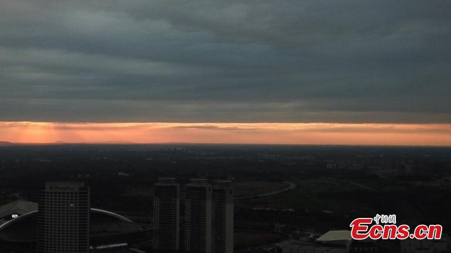 Dark clouds create a distinct line in the sky as the sun sets over Yangzhou City, Jiangsu Province, Aug. 21, 2018. The sunset created an intense orange glow that contrasted with the dark clouds, creating a spectacular natural wonder. (Photo: China News Service/Meng Delong)