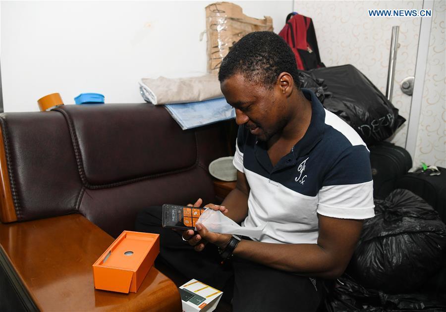 Mansur Barhama Abulfathi from Nigeria checks a Chinese-made smartphone to be brought back to his hometown in Guangzhou, south China\'s Guangdong Province, Aug. 15, 2018. This 24-year-old young man has a Chinese name Quan Xiaobao. Quan Xiaobao has lived in Guangzhou for over one year, and his fluency in Chinese allows him to work part-time as a translator and business consultant. Located near Hong Kong and Macao special administrative regions, Guangzhou attracts many Africans to work or study here. Guangzhou government has stepped up the work to provide all-round service for foreigners to help them adapt to the local environment. (Xinhua/Deng Hua)