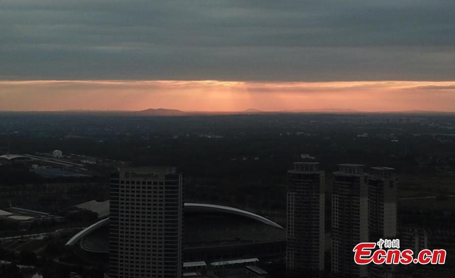 Dark clouds create a distinct line in the sky as the sun sets over Yangzhou City, Jiangsu Province, Aug. 21, 2018. The sunset created an intense orange glow that contrasted with the dark clouds, creating a spectacular natural wonder. (Photo: China News Service/Meng Delong)