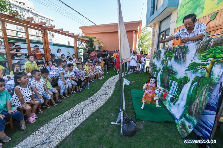 The 71-year-old puppet show player Jiang Wanbao performs for children at a kindergarten in Changxing County, east China\'s Zhejiang Province, Aug. 30, 2018. The school prepares various activities for children to learn about traditional Chinese culture at the beginning of the new semester. (Xinhua/Xu Yu)