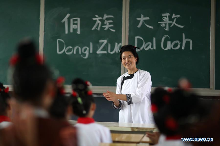 Folk artist Yang Huanzhen teaches pupils to sing songs of Kam Grand Choir, the polyphonic choir singing, at Jiali Primary School in Zaima Town of Rongjiang County, southwest China\'s Guizhou Province, Aug. 29, 2018. Schools in China prepared many activities for students to greet the new semester after summer vacation. (Xinhua/Yang Chengli)