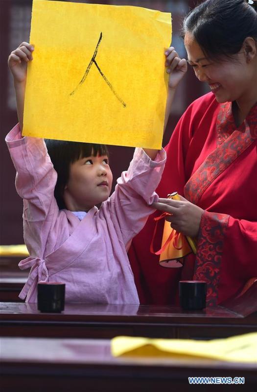 A newly-enrolled pupil presents her calligraphy work of a Chinese character \