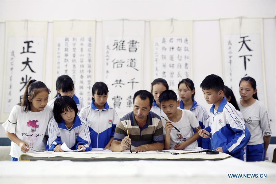 A teacher demonstrates Chinese calligraphy skills for students during an activity at the first lesson of the new term at the Danzhai No. 3 Middle School in Danzhai County, southwest China\'s Guizhou Province, Aug. 29, 2018. Schools in China prepared many activities for students to greet the new semester after summer vacation. (Xinhua/Huang Xiaohai)