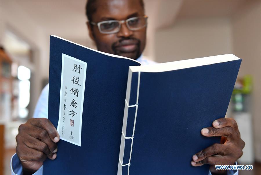 Diarra reads a book of traditional Chinese medicine at home in Kunming, southwest China\'s Yunnan Province, Aug. 28, 2018. (Xinhua/Lin Yiguang)