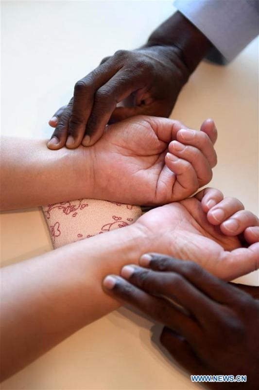 Diarra feels the pulse of a woman in Kunming, southwest China\'s Yunnan Province, Aug. 28, 2018. (Xinhua/Lin Yiguang)