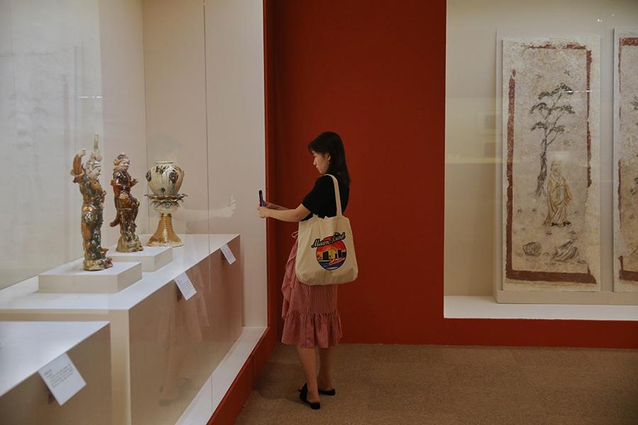 A visitor takes photos of exhibited artifacts. (Photo/China Daily)