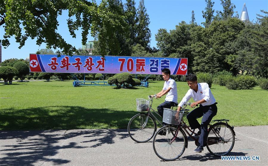 Photo taken on Sept. 8, 2018 shows residents riding pass a poster of National Day celebration in Pyongyang, capital of the Democratic People\'s Republic of Korea (DPRK). Sept. 9, 2018 marks the 70th anniversary of the founding of the DPRK. (Xinhua/Jiang Yaping)