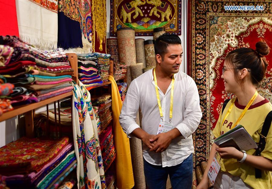 An exhibitor from India introduces scarfs to a visitor at the 20th China International Fair for Investment and Trade in Xiamen, southeast China\'s Fujian Province, Sept. 8, 2018. (Xinhua/Wei Peiquan)