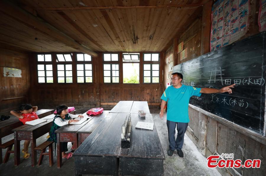 Yang Changjun teaches Chinese to Wang Fangying (C), a first grader, while his daughter, 6, also sits in the classroom at a school in Danggan Village, Paitiao Town, Guizhou Province, Sept. 7, 2018. Yang, 40, is the only teacher in the school that has one first grader and seven pre-school children from nearby villages. If not for the school, children would have to travel to a town more than 20 kilometers away to study. (Photo: China News Service/Huang Xiaohai)
