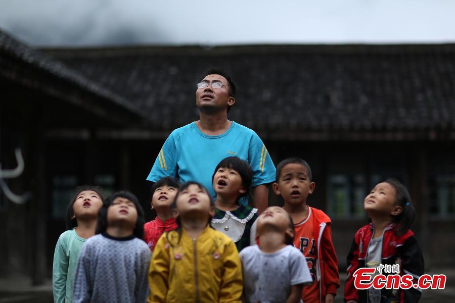 Yang Changjun leads children in the flag-raising ceremony at a school in Danggan Village, Paitiao Town, Guizhou Province, Sept. 7, 2018. Yang, 40, is the only teacher in the school that has one first grader and seven pre-school children from nearby villages. If not for the school, children would have to travel to a town more than 20 kilometers away to study. (Photo: China News Service/Huang Xiaohai)
