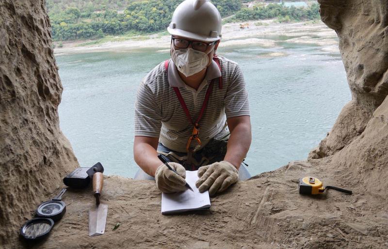 An archaeological worker writes down data about a rock tomb in Yangpitan, Yunxi county, Central China\'s Hubei Province. (Photo by Zhang Jianbo for chinadaily.com.cn)