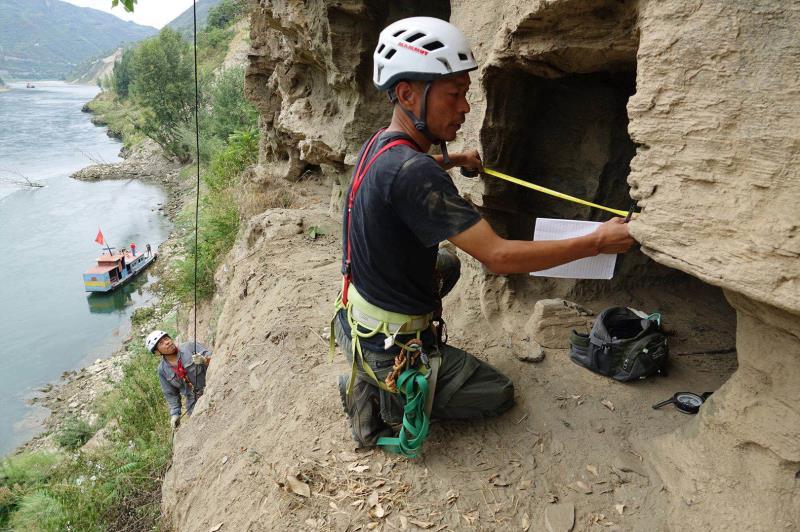 An archaeological worker measures the width of the opening of a rock tomb in Yangpitan, Yunxi county, Central China\'s Hubei Province. (Photo by Zhang Jianbo for chinadaily.com.cn)