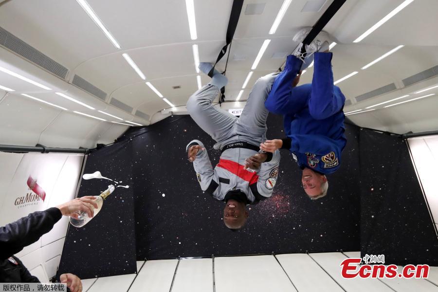 Sprinter Usain Bolt and French astronaut Jean-Francois Clervoy, CEO of Novespace, are sprayed with champagne from a bottle of \