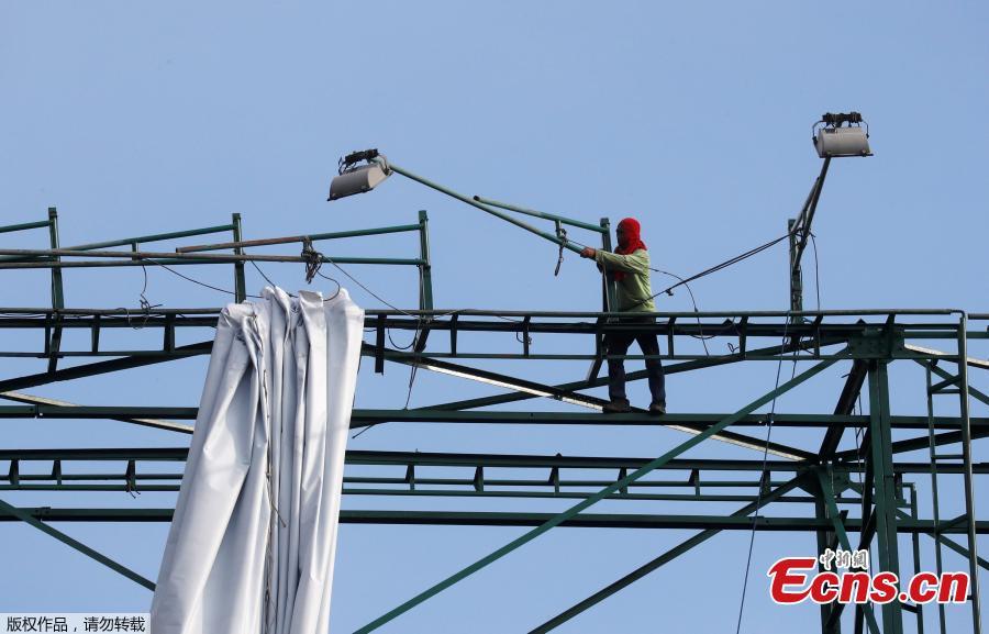A worker adjusts a spotlight of an advertising billboard along main road EDSA in preparation for the coming of Super Typhoon Mangkhut before it hits the main island of Luzon, in Quezon City, Metro Manila, Philippines, Sept. 12, 2018. (Photo/Agencies)