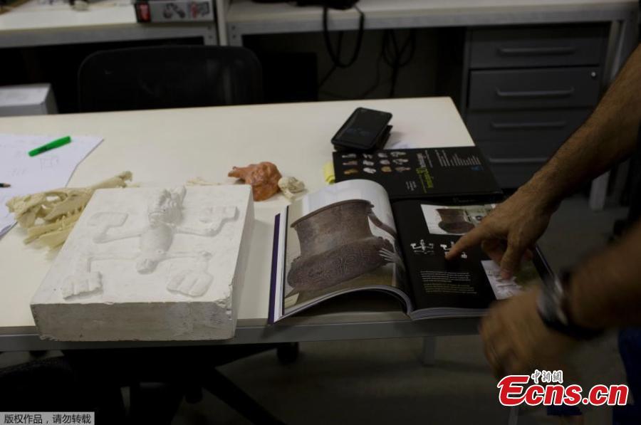 Jorge Lopes, researcher at the Pontifical Catholic University, shows a book with pictures of originals and replicas of some of the artifacts that were inside the National Museum, in Rio de Janeiro, Brazil, Sept. 5, 2018. About 300 pieces of the Brazil\'s National Museum that were scanned and some printed in 3D could help to rebuild part of the heritage lost in the fire this weekend. Since 2000, researchers at the PUC worked together with the museum, scanning and printing some of the most important objects of the institution. (Photo/Agencies)