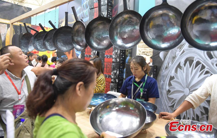 Visitors choose Zhangqiu Iron Pan at the fifth China Intangible Cultural Heritage Expo in Jinan City, Shandong Province, Sept. 13, 2018. The expo was jointly organized by the Ministry of Culture and Tourism and the Shandong provincial government. More than 200 practitioners of traditional arts and craftsmanship will showcase their skills at the expo, which will include stilt-walking, embroidery by the Qiang people and straw-weaving craftworks. (Photo: China News Service/Zhang Yong)