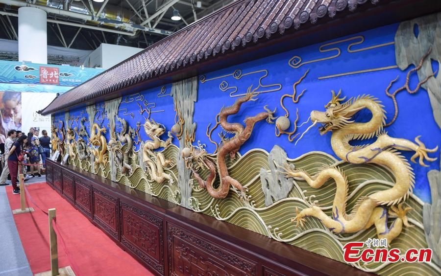 Visitors are attracted by the Nine-Dragon-Wall at the fifth China Intangible Cultural Heritage Expo in Jinan City, Shandong Province, Sept. 13, 2018. The expo was jointly organized by the Ministry of Culture and Tourism and the Shandong provincial government. More than 200 practitioners of traditional arts and craftsmanship will showcase their skills at the expo, which will include stilt-walking, embroidery by the Qiang people and straw-weaving craftworks. (Photo: China News Service/Zhang Yong)