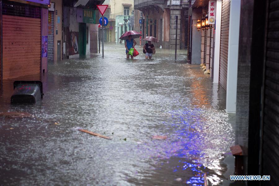 Citizens walk along a waterlogged road in Macao, south China, Sept. 16, 2018. Macao has upgraded its typhoon signal to highest No.10 level on Sunday at 11:00 a.m. local time, as Typhoon Mangkhut approaches with raging storms. (Xinhua/Cheong Kam Ka)