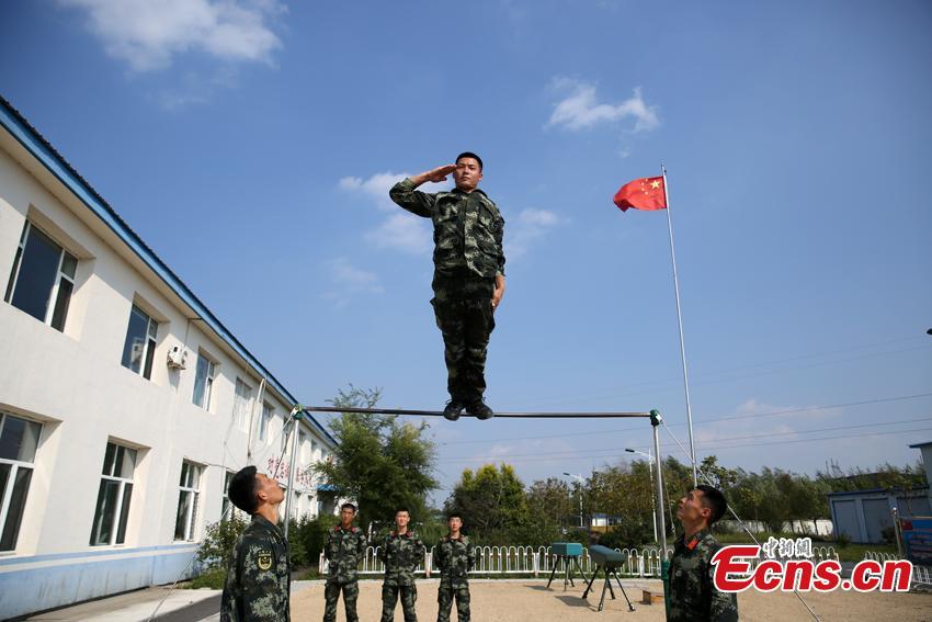 Armed police Kang Lidong salutes while standing on a horizontal bar during training in Meihekou City, Northeast China’s Jilin Province. The Kang brothers joined the army together and have won a number of awards although they have different personalities and gifts. (Photo: China News Service/Liang Yonggang)