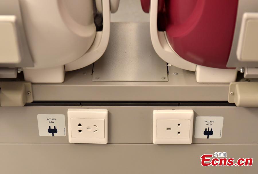 Power sockets suitable for different electrical standards are available in the front of seats on a high-speed train used for the Guangzhou-Shenzhen-Hong Kong Express Rail Link, Sept. 23, 2018. The first-class seats feature soft lighting, seats in different colors, as well as rose patterns on the floor. (Photo: China News Service/Zhang Wei)