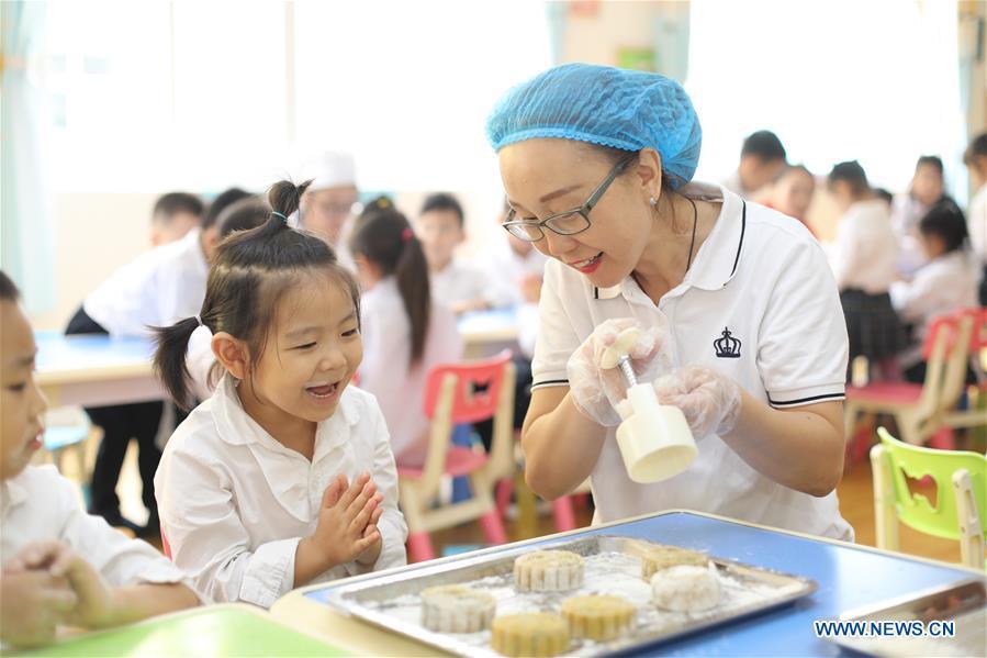Children learn to make mooncakes at a kindergarten to greet the traditional Mid-Autumn Festival in Gucheng County, north China\'s Hebei Province, Sept. 21, 2018. The Mid-Autumn Festival falls on the 15th day of the eighth month of the Chinese lunar calendar, or Sept. 24 this year. (Xinhua/Zhu Xudong)