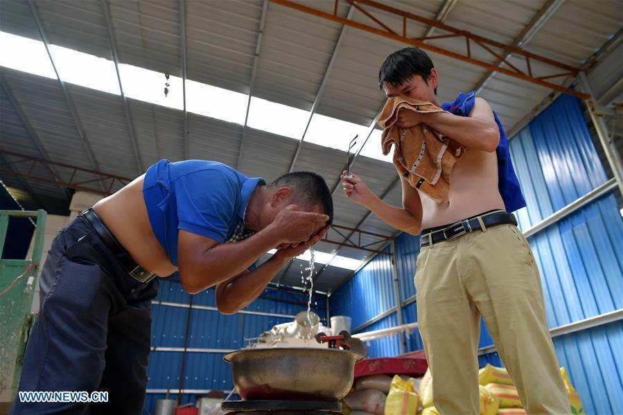 Zhou Xiaolin (L) and Zhou Biao wash their faces after their morning work in Liutian Village of Xinjian District in Nanchang, east China\'s Jiangxi Province, Sept. 20, 2018. When every harvest season for middle-season rice begins in September, Zhou Xiaolin, a rice grower, and his son Zhou Biao will always offer help to other farmers with the harvest, because few families nearby own multiple farm machineries that suffice the workload. Born in Liutian Village, Zhou Xiaolin used to be a carpenter away from home. In 2005, he returned home to take on rice growing. Two years later, Zhou Xiaolin and Zhou Biao expanded the scale of their rice growing by contracting to take over the village\'s uncultivated croplands. To meet the increasing production demand, Zhou bought the first farm machine in the village. Currently, Zhou Xiaolin and Zhou Biao have nearly 50 hectares of farmland under cultivation in the village. Altogether they own two combine harvesters, two rice transplanters and a tractor, which have made production even more efficient. An increasing number of rice growers nearby have started to use Zhou Xiaolin\'s machines and services for a reasonable price. \