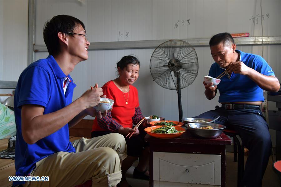 Zhou Xiaolin (R) and and his family have lunch in Liutian Village of Xinjian District in Nanchang, east China\'s Jiangxi Province, Sept. 20, 2018. When every harvest season for middle-season rice begins in September, Zhou Xiaolin, a rice grower, and his son Zhou Biao will always offer help to other farmers with the harvest, because few families nearby own multiple farm machineries that suffice the workload. Born in Liutian Village, Zhou Xiaolin used to be a carpenter away from home. In 2005, he returned home to take on rice growing. Two years later, Zhou Xiaolin and Zhou Biao expanded the scale of their rice growing by contracting to take over the village\'s uncultivated croplands. To meet the increasing production demand, Zhou bought the first farm machine in the village. Currently, Zhou Xiaolin and Zhou Biao have nearly 50 hectares of farmland under cultivation in the village. Altogether they own two combine harvesters, two rice transplanters and a tractor, which have made production even more efficient. An increasing number of rice growers nearby have started to use Zhou Xiaolin\'s machines and services for a reasonable price. \