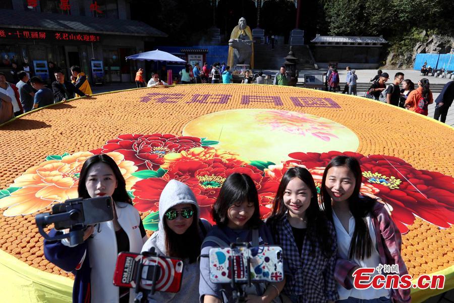 People take photos before a beautiful pattern with Chinese characters of Hua Hao Yue Yuan (Blooming flowers and full moon) spelt out with 9,999 mooncakes at Laojun Mountain, a scenic spot in Luoyang City, Central China’s Henan Province, Sept. 23, 2018. (Photo: China News Service/Wang Zhongju)