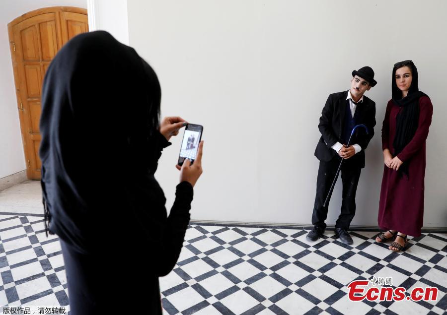 A woman takes a picture of Afghanistan\'s Charlie Chaplin, Karim Asir, 25, after his performance in Kabul, Afghanistan, Aug. 29, 2018. Karim Asir says he has witnessed suicide attacks, explosions and threats from hardline Islamic militant groups, but is determined to waddle and bumble to fulfill the primary goal of his life. (Photo/Agencies)