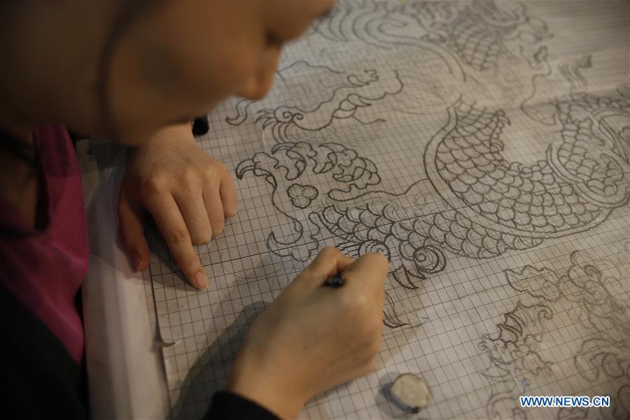 A weaver draws a pattern before weaving Yun brocade at the Nanjing Yunjin Museum in Nanjing, capital of east China\'s Jiangsu Province, Sept.26, 2018. Yunjin, also called Yun brocade, is traditional Chinese silk brocade made in Nanjing of Jiangsu. Dated from the Eastern Jin Dynasty, it has formed its own characteristics through its development of 1,600 years. Yun brocade is famous for its exquisite craft, elegant patterns and smooth texture, and the making of the artwork requires close cooperation of two weavers, who can produce only five centimeters a day. In 2009, Yun brocade was inscribed on the Representative List of the Intangible Cultural Heritage of Humanity. (Xinhua/Zhu Weixi)