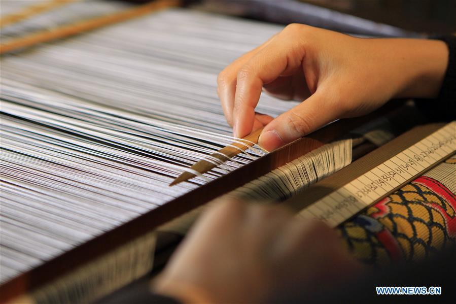 A weaver shows skills of weaving Yun brocade at the Nanjing Yunjin Museum in Nanjing, capital of east China\'s Jiangsu Province, Sept.26, 2018. Yunjin, also called Yun brocade, is traditional Chinese silk brocade made in Nanjing of Jiangsu. Dated from the Eastern Jin Dynasty, it has formed its own characteristics through its development of 1,600 years. Yun brocade is famous for its exquisite craft, elegant patterns and smooth texture, and the making of the artwork requires close cooperation of two weavers, who can produce only five centimeters a day. In 2009, Yun brocade was inscribed on the Representative List of the Intangible Cultural Heritage of Humanity. (Xinhua/Sui Xiankai)