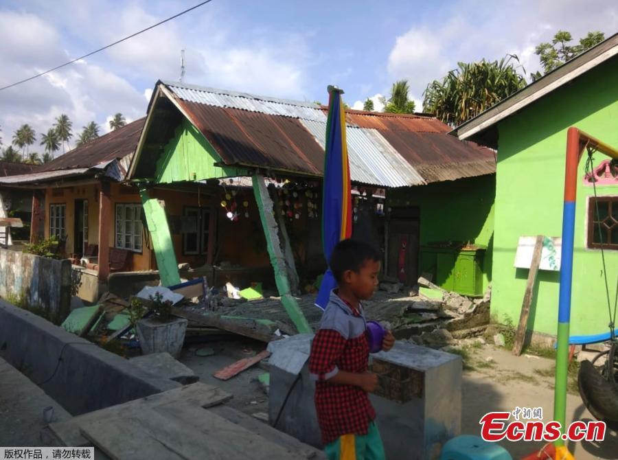 A handout photo made available by the Indonesian National Board for Disaster Management (BNPB) shows a boy walking in front of a collapsed house after an earthquake in Donggala, Central Sulawesi, Indonesia, Sept. 28, 2018. A tsunami caused deaths when it hit a small city on the Indonesian island of Sulawesi on Friday after a major quake, collapsing buildings and cutting off power, officials said, although the exact number of casualties was not clear.(Photo/Agencies)