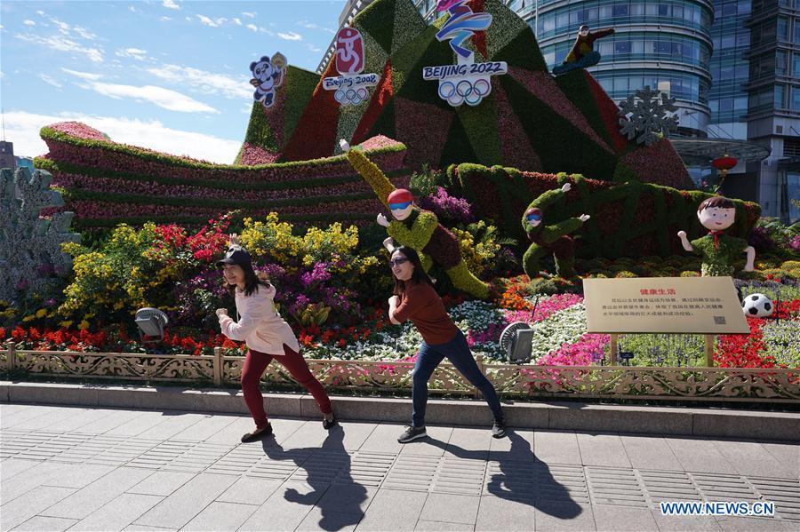 Two tourists pose for photos with flower parterres in Beijing, capital of China, Sept. 29, 2018. Beijing is decorated with ornamental flower parterres for the upcoming China\'s National Day. (Xinhua/Ju Huanzong)