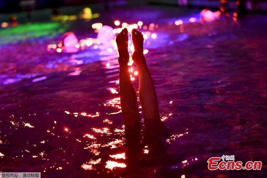 People swim in the lighted water of the Hirschengraben indoor swimming pool in Bern during an artistic performance by Swiss visual artist Pipilotti Rist and World Wide Fund for Nature (WWF) Switzerland non-governmental organization to denounce the disappearance of corals due to the warming and the acidification of the ocean on October 7, 2018. (Photo/Agencies)