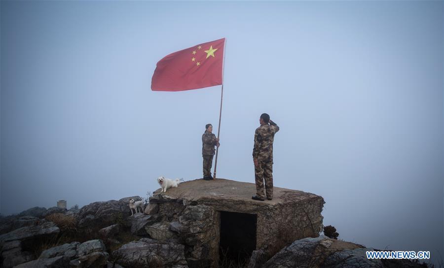 Wang Jicai (R) salutes the national flag on Kaishan Island of Guanyun County, east China\'s Jiangsu Province, Jan. 1, 2017. Wang Jicai, who used to be head of the militia post on Kaishan Island in Jiangsu Province, started working on the island in the Yellow Sea with his wife in 1986. He died of sudden illness while on duty in July of 2018 at the age of 58. Wang Zhiguo, son of Wang Jicai, became a frontier defence policeman after his graduation from Nanjing University of Aeronautics and Astronautics in 2013. He had been assigned to many security tasks for major events during 5 years\' working. (Xinhua/Li Xiang)