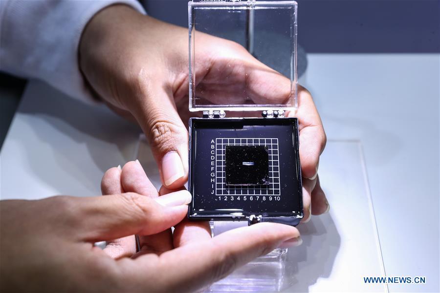 A staff member shows a photonic AI chip during a press preview of the 2018 National Mass Innovation and Entrepreneurship Week in Beijing, capital of China, Oct. 8, 2018. The weekly event will run from October 9 to 15. (Xinhua/Zhang Yuwei)