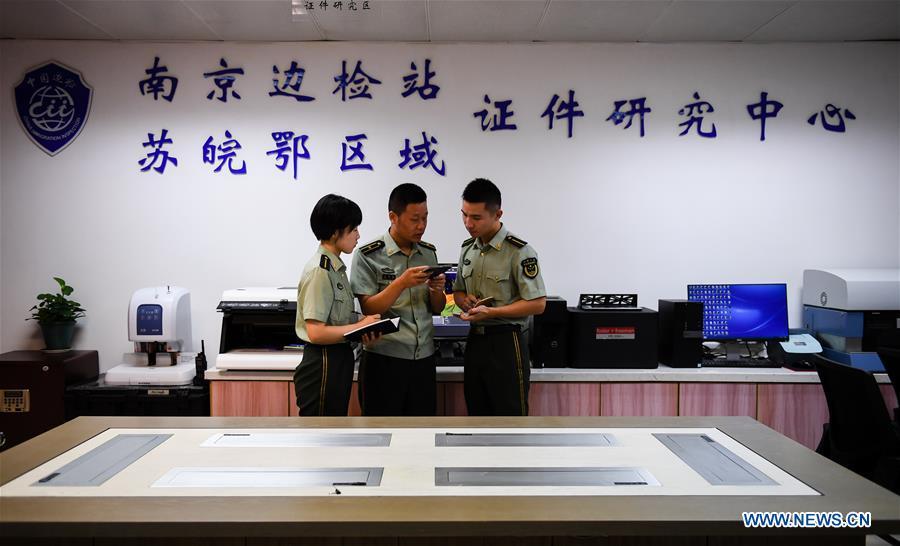 Wang Zhiguo (C) discusses on certificate identification with colleagues at Nanjing Lukou International Airport in Nanjing, capital of east China\'s Jiangsu Province, Aug. 7, 2018. Wang Jicai, who used to be head of the militia post on Kaishan Island in Jiangsu Province, started working on the island in the Yellow Sea with his wife in 1986. He died of sudden illness while on duty in July of 2018 at the age of 58. Wang Zhiguo, son of Wang Jicai, became a frontier defence policeman after his graduation from Nanjing University of Aeronautics and Astronautics in 2013. He had been assigned to many security tasks for major events during 5 years\' working. (Xinhua/Li Xiang)