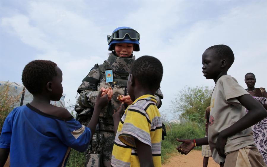 Jia Xiaochen, a Chinese peacekeeper in the infantry squad shares candy with children in Juba. (Photo/Xinhua)
Growing stature
Joining the battalion at its camp during the Army Day celebrations, the deputy head of UNMISS, Moustapha Soumare, said the presence of Chinese peacekeepers was reassuring, given the complex situation and volatility in South Sudan.
\