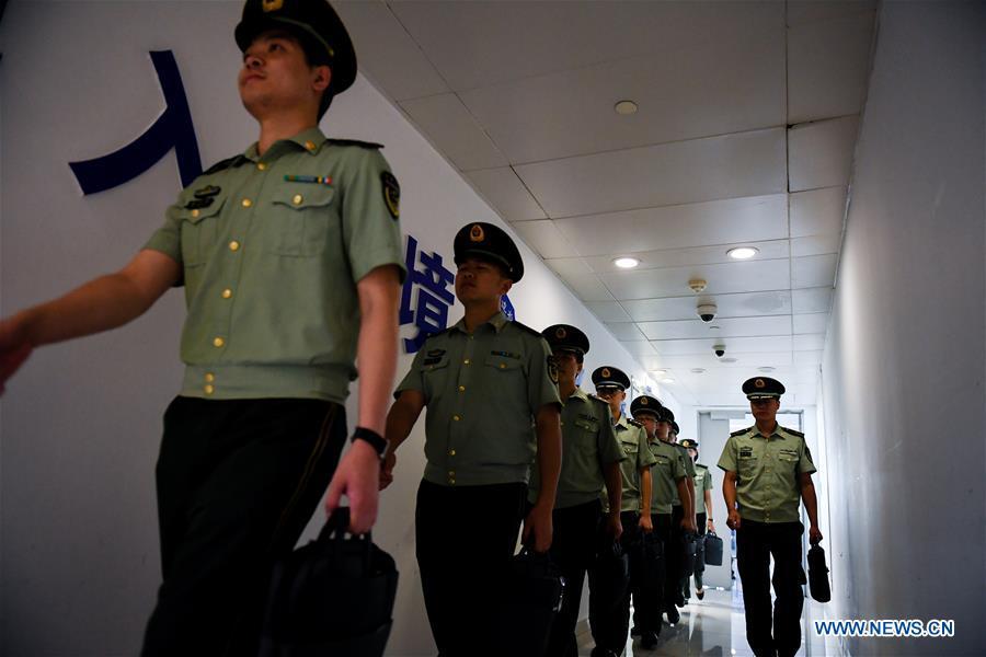 Wang Zhiguo (1st R) perpares to work at Nanjing Lukou International Airport in Nanjing, capital of east China\'s Jiangsu Province, Aug. 7, 2018. Wang Jicai, who used to be head of the militia post on Kaishan Island in Jiangsu Province, started working on the island in the Yellow Sea with his wife in 1986. He died of sudden illness while on duty in July of 2018 at the age of 58. Wang Zhiguo, son of Wang Jicai, became a frontier defence policeman after his graduation from Nanjing University of Aeronautics and Astronautics in 2013. He had been assigned to many security tasks for major events during 5 years\' working. (Xinhua/Li Xiang)